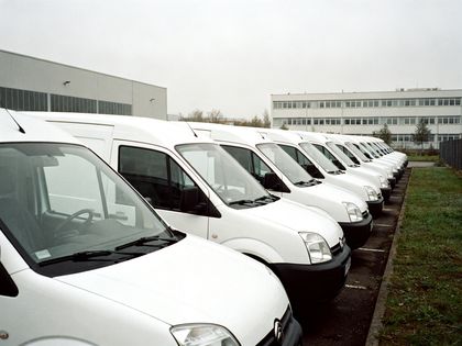 Reihe weißer Transporter ohne Beschriftung auf einem Firmenhof